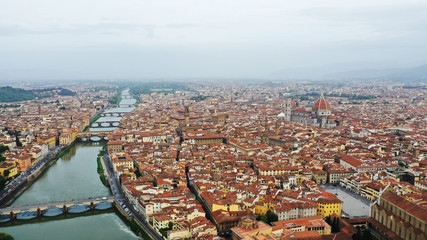 Aerial view of Ponte Vecchio bridge on Arno river in Florence city center, Italy. Italian orange roofs from drone near Cathedral. Tuscany.