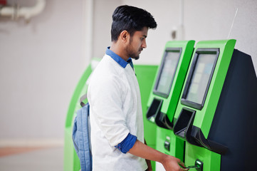 Young asian man put his credit card for removes cash from an green ATM.