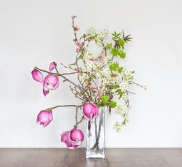 Beautiful sprig floral composition with pink magnolia. Spring interior decoration.