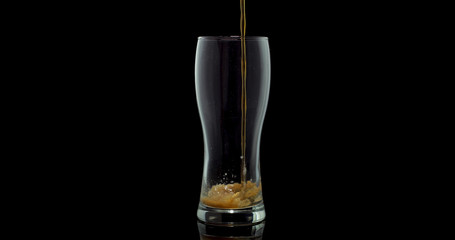 Dark craft beer brewed from malt and barley in a private brewery on a black background poured into a glass for the Oktoberfest festival