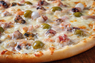 Pizza with shrimp and olives close-up.