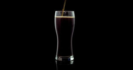 craft beer brewed from natural, environmentally friendly malt and barley in a private brewery on a black background poured into a glass for the Oktoberfest festival.