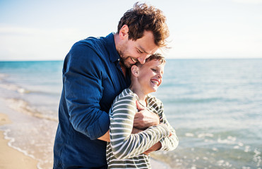 Father with two small son on a walk outdoors on beach, having fun.