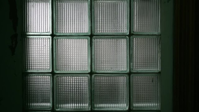 Close-up of Glass bricks pattern window in a dark room with reflection lighting behind. Abstract block walls for the design background. Surface of the glass in interior. Security concept from USSR.