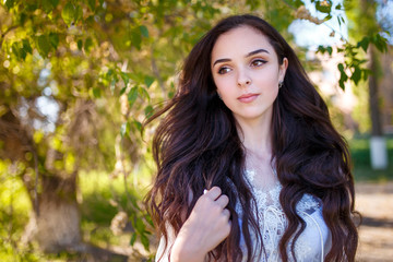 portrait of a teenager girl in white dress with long dark wavy hair 