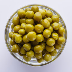 canned green peas in a glass bowl on a white background