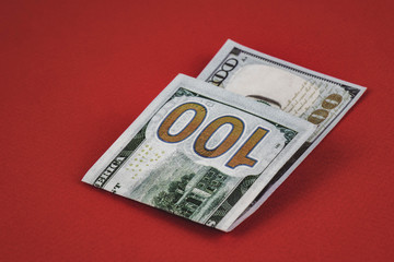 one hundred dollars lying on red background close up.