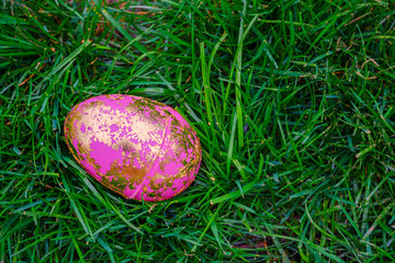 Colorful easter pink golden easter egg on grass background