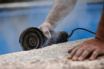 Worker with radial saw with dust on the air with blue background