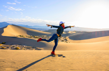Women flying pose standing on the desert dudes with sunshine morning over blue sky background