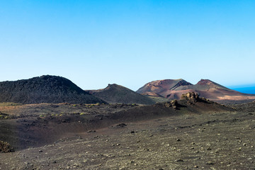 Fototapeta na wymiar Timanfaya National Park, mountains of fire at Lanzarote, Canary Islands, Spain. Unique panoramic view of spectacular lava river flows from huge volcano craters.