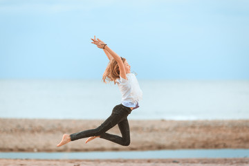 Fototapeta premium Young girl jumping in the air on the beach