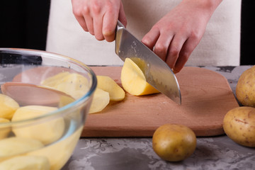 young woman in an apron cuts potatoes