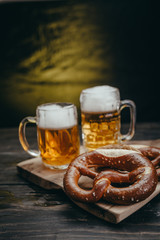 pretzels and draft beer on rustic cutting board against dark background