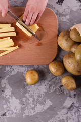young woman in an apron cuts potatoes