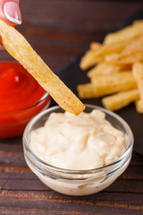 young woman dip french fries to mayonnaise sauce