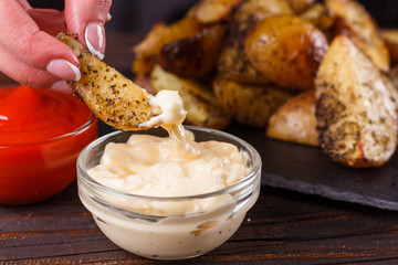 young woman dip fried potatoes to mayonnaise sauce