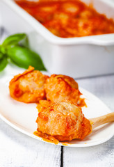 Meatballs with tomato and sour cream sauce on white plate. Close up