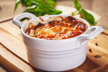 Celery root gratin with cheese and mushrooms on wooden board. Close up
