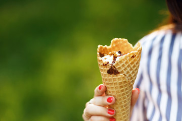Ice cream close-up. Young beautiful girl with long flowing hair holding ice cream. Bright sunny day. Natural background. Soft focus. Summer concept