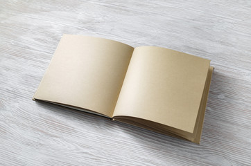 Blank notepad or book of kraft paper on light wooden background. Mockup for your design.