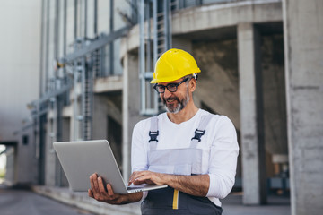 worker using laptop in front of grain silos