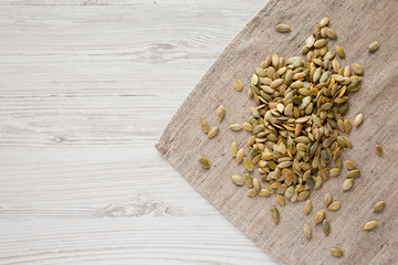 Roasted pumpkin seeds on a white wooden background, top view. Flat lay, overhead, from above. Copy space.