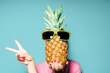 Woman and pineapple on her head standing over color background