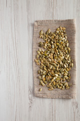 Roasted pumpkin seeds on a white wooden surface, top view. Flat lay, overhead, from above. Copy space.
