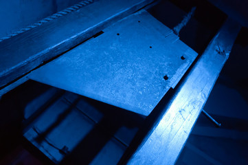 Blade of a guillotine lit with blue light