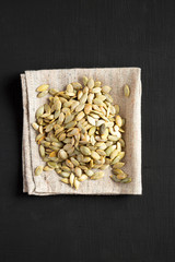 Roasted pumpkin seeds on a black surface, top view. Flat lay, overhead, from above.