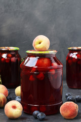 Compote with peaches and berries of blackthorn in cans located on a dark background, Harvest for...