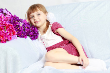 Obraz na płótnie Canvas Girl sits next to a bouquet of flowers.