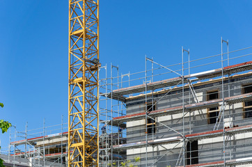 building under construction - construction site with crane and scaffolding at the facade