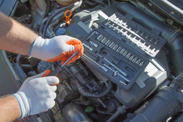 The mechanic's hands on the background of the open bonnet repairs the details
