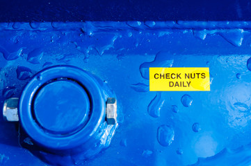 Notice on a machine warning users to "Check nuts daily"