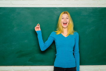 Student, teacher near blackboard, chalkboard. Student writing on blackboard in classroom. Teacher standing near blackboard in classroom. Student at exam. Education. Teacher in school room during class