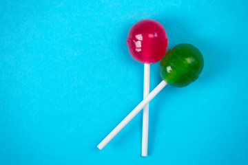Candies on a stick, on a blue background with the copy of space. Top view, sweet caramel.