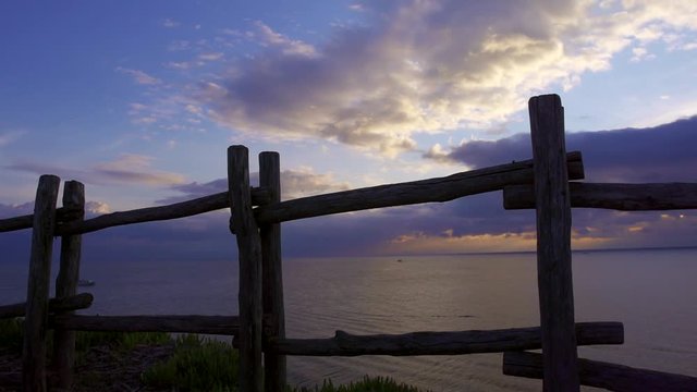 panoramic shot of calm sea in sunset time in cloudy weather, view through fence