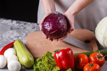 a young woman in a gray apron cuts red cabbage
