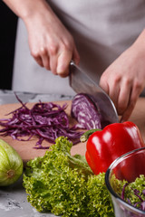 a young woman in a gray apron cuts red cabbage