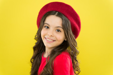 Kid girl long healthy shiny hair wear red hat. Little girl with long hair. Kid happy cute face adorable curly hair yellow background. Lucky and beautiful. Beauty tips for tidy hair. Smiling child