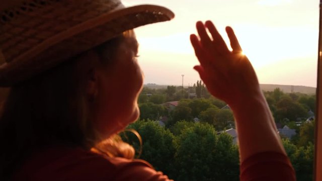Elderly woman emotionally waving from the balcony to someone