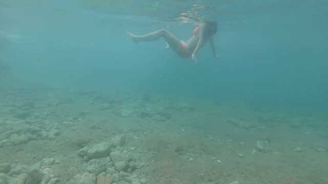 Girl with beautiful figure is swimming on the beach. Underwater shooting.
