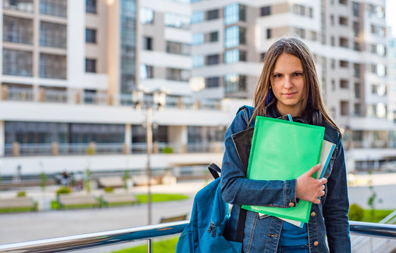 Back to school student teenager girl holding books and note books wearing backpack. Outdoor portrait of young teenager brunette girl with long hair. girl on city