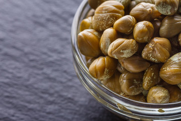 pickled capers on a dark stone background