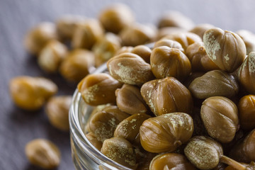 pickled capers on a dark stone background