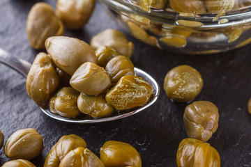 pickled capers on a dark stone background