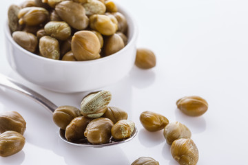 Pickled capers on a white acrylic background