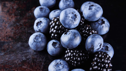 Blueberries and blackberries on dark background. Fresh berries for vegan. Assorted berries on rusty background. Flat lay